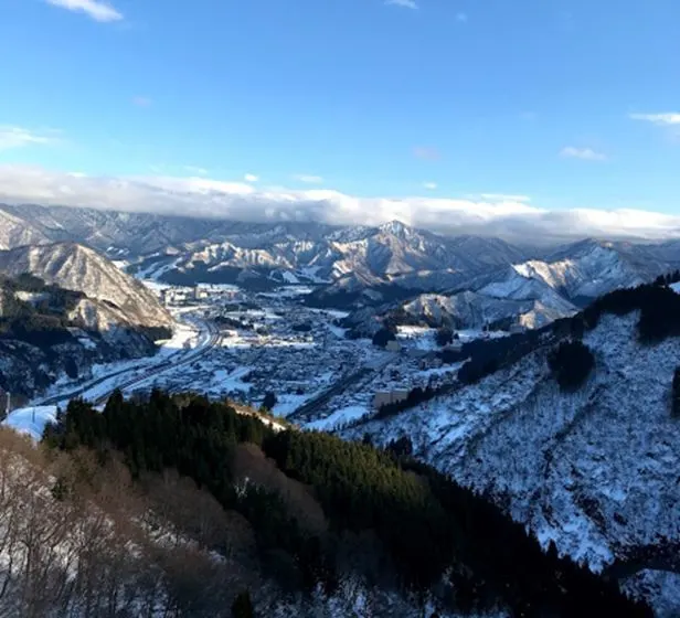 Snow-covered mountains and the town of Yuzawa under a blue sky